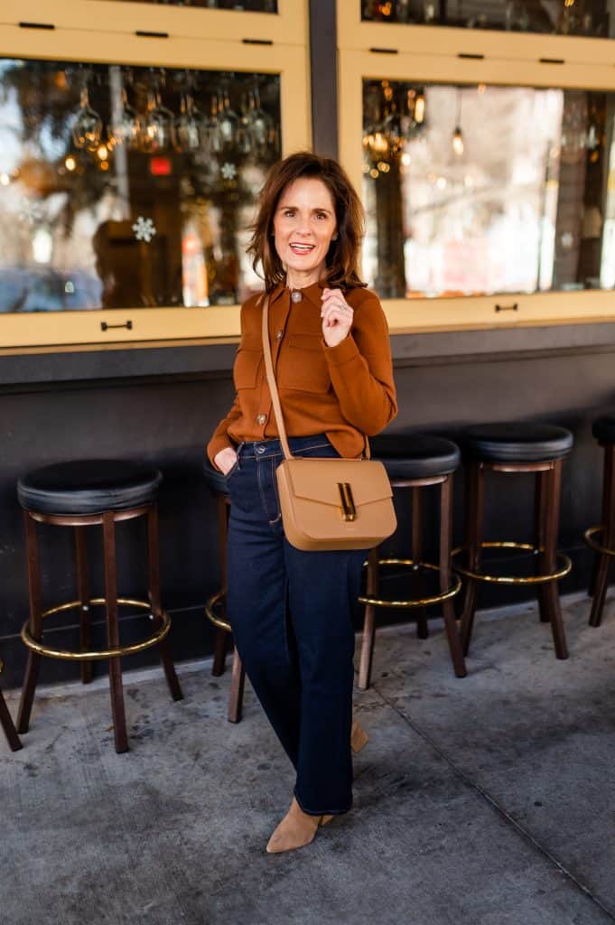brunette woman wearing a bronze sweater, wide leg jeans, and tan pointy toe booties, pointy toe booties are one of the best shoes to wear with wide leg pants