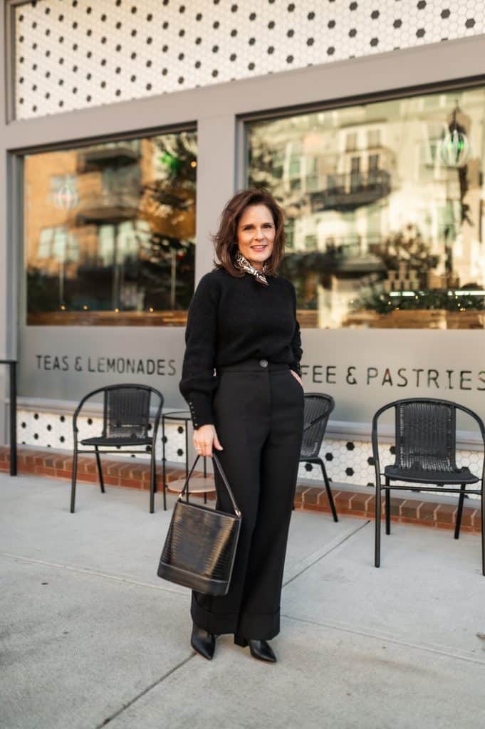 petite woman wearing a black sweater and black damon sezane trouser with black boots for a chic look