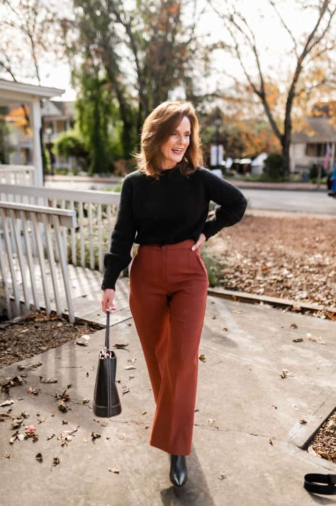 petite brunette woman wearing a black sweater and brown martin cropped Sezane trousers with black boots