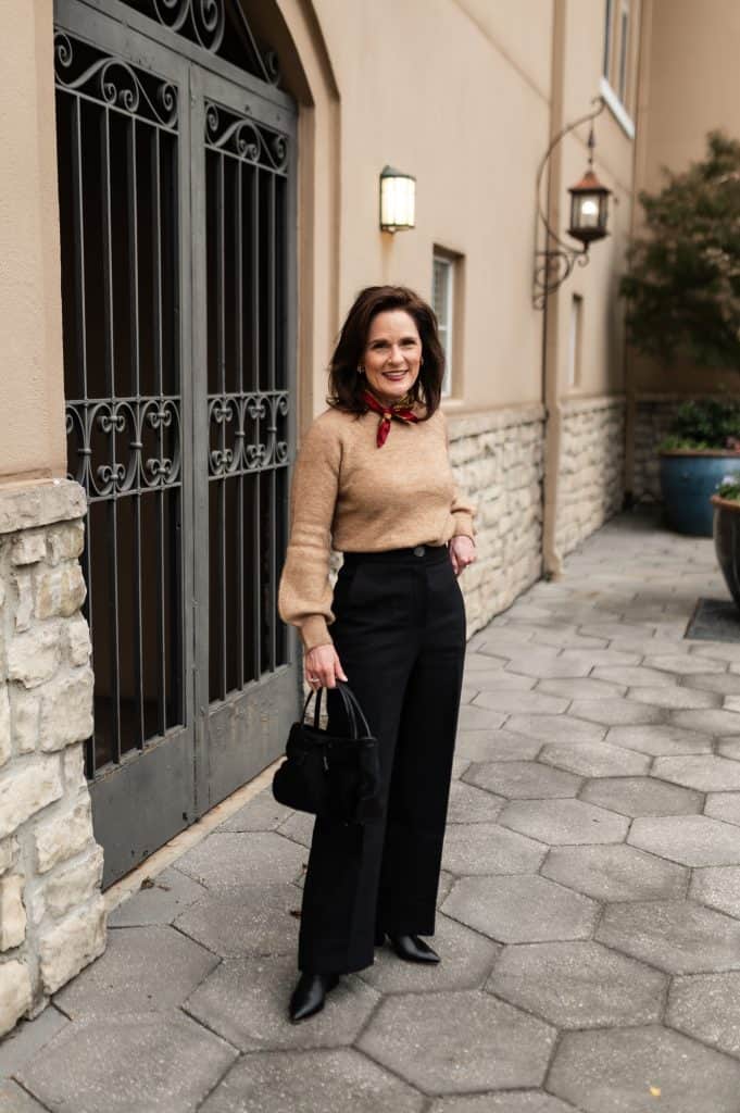 petite brunette woman wearing a camel sweater with black damon Sezane trousers and black boots