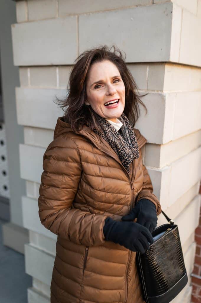 petite brunette woman wearing a puffer jacket with winter accessories of fleece scarf and fleece gloves