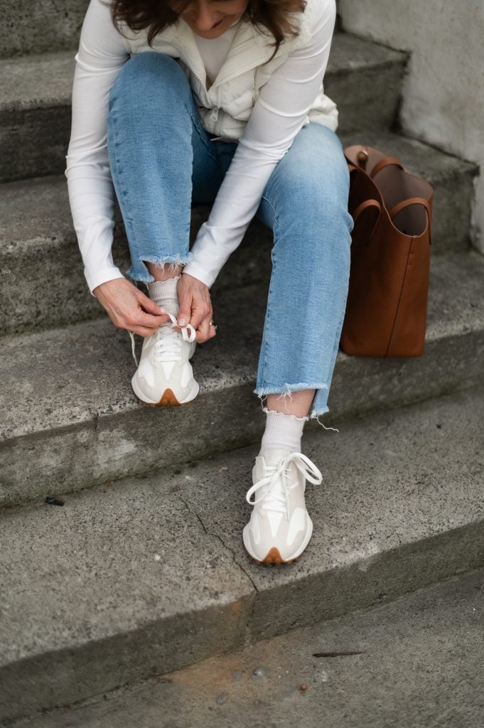Cropped jeans styled with sneakers and socks for winter on a petite frame.
