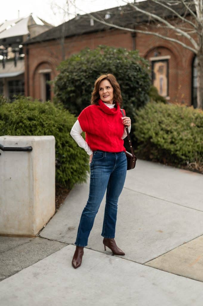 Dressed up winter outfit with cropped jeans, ankle boots, and a sweater vest on a petite frame.